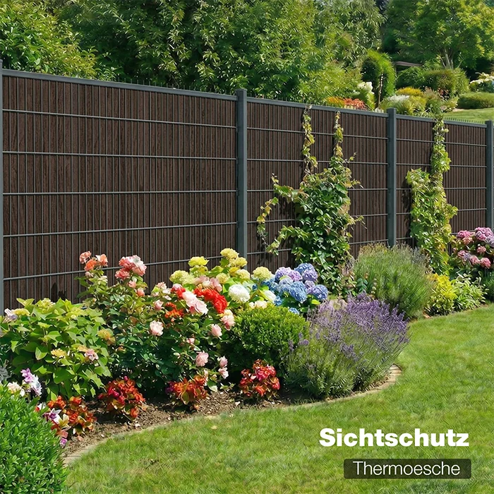 Sichtschutzzaun Vollholz Thermoesche  als Gartenzaun mit blühendem Beet im Hintergrund